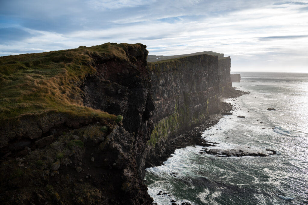 Sea cliffs at Látrabjarg in the Westfjords, Iceland, in autumn — the clifftop grass and Atlantic ocean below, photographed after the puffin season had ended
