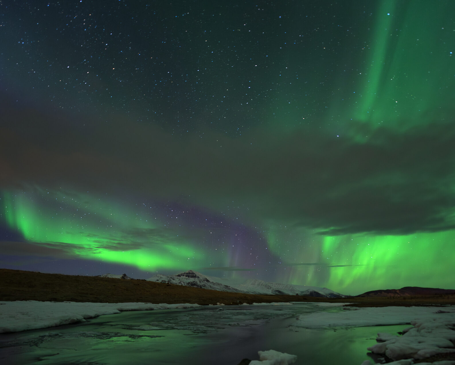 Green aurora over a snow-covered mountain in Iceland