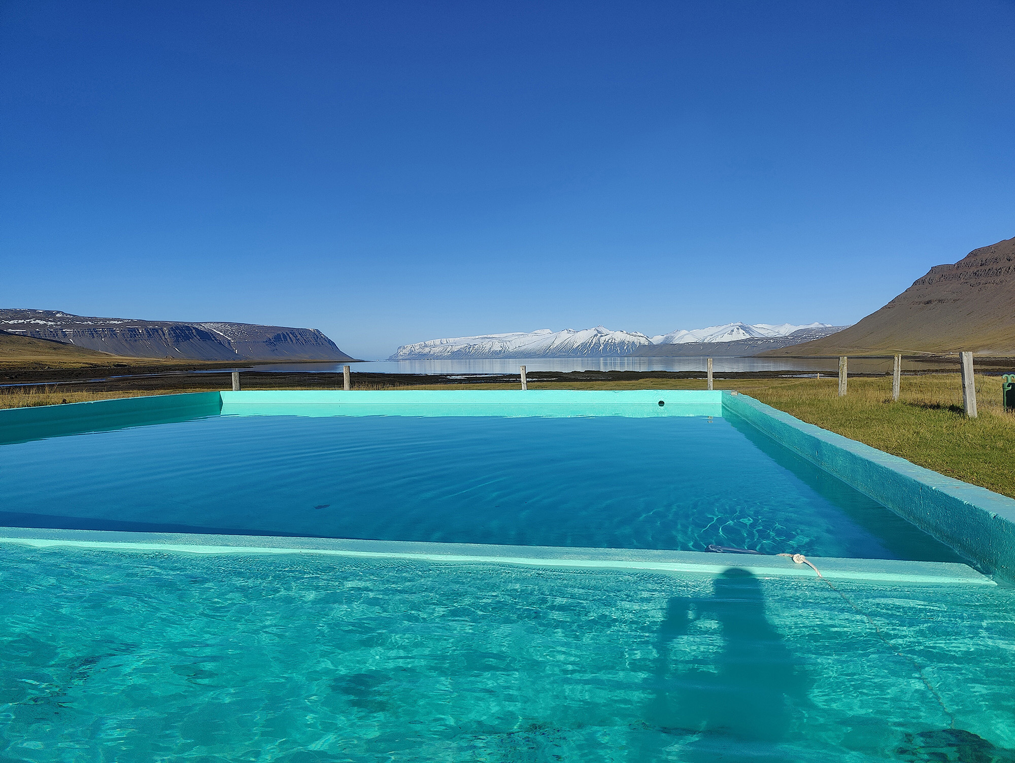 Reykjafjarðarlaug natural hot pool with fjord and snow-capped mountains, Westfjords, Iceland — photographed by Marcel Strobel