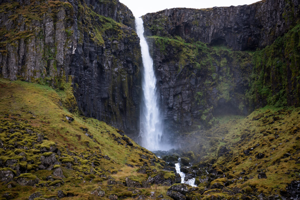 Waterfall with autumn-coloured moss and grass in a basalt canyon, East Iceland — photographed by Marcel Strobel