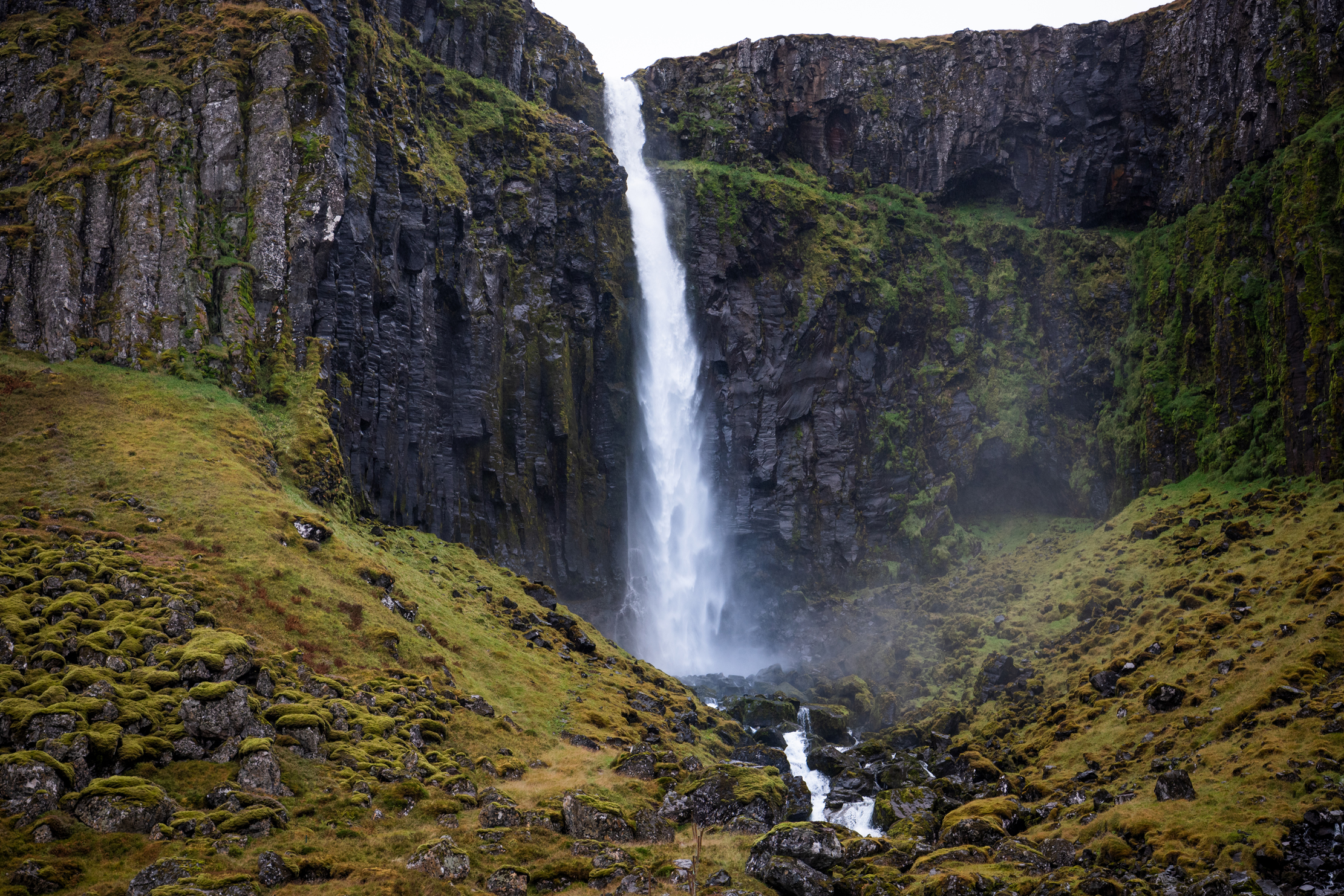 Waterfall with autumn-coloured moss and grass in a basalt canyon, East Iceland — photographed by Marcel Strobel